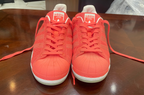 Pair of red Adidas sneakers on a wooden surface
