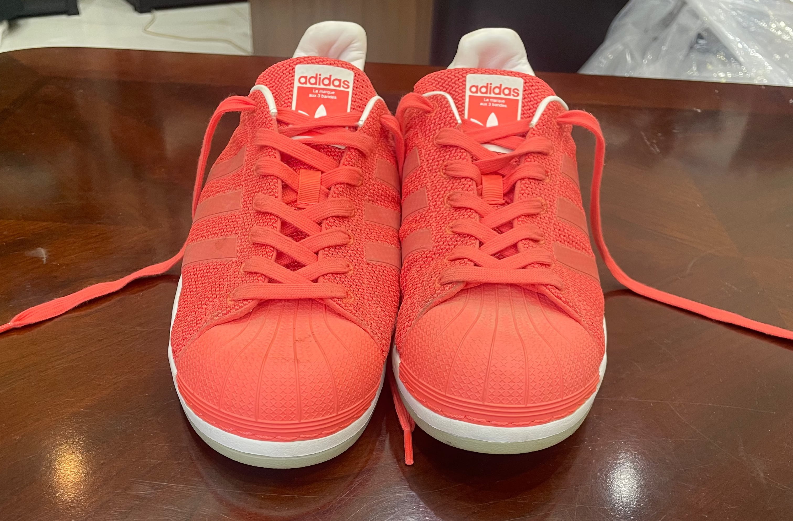 Pair of red Adidas sneakers on a wooden surface