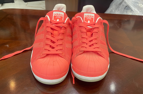 Pair of red Adidas sneakers on a wooden surface